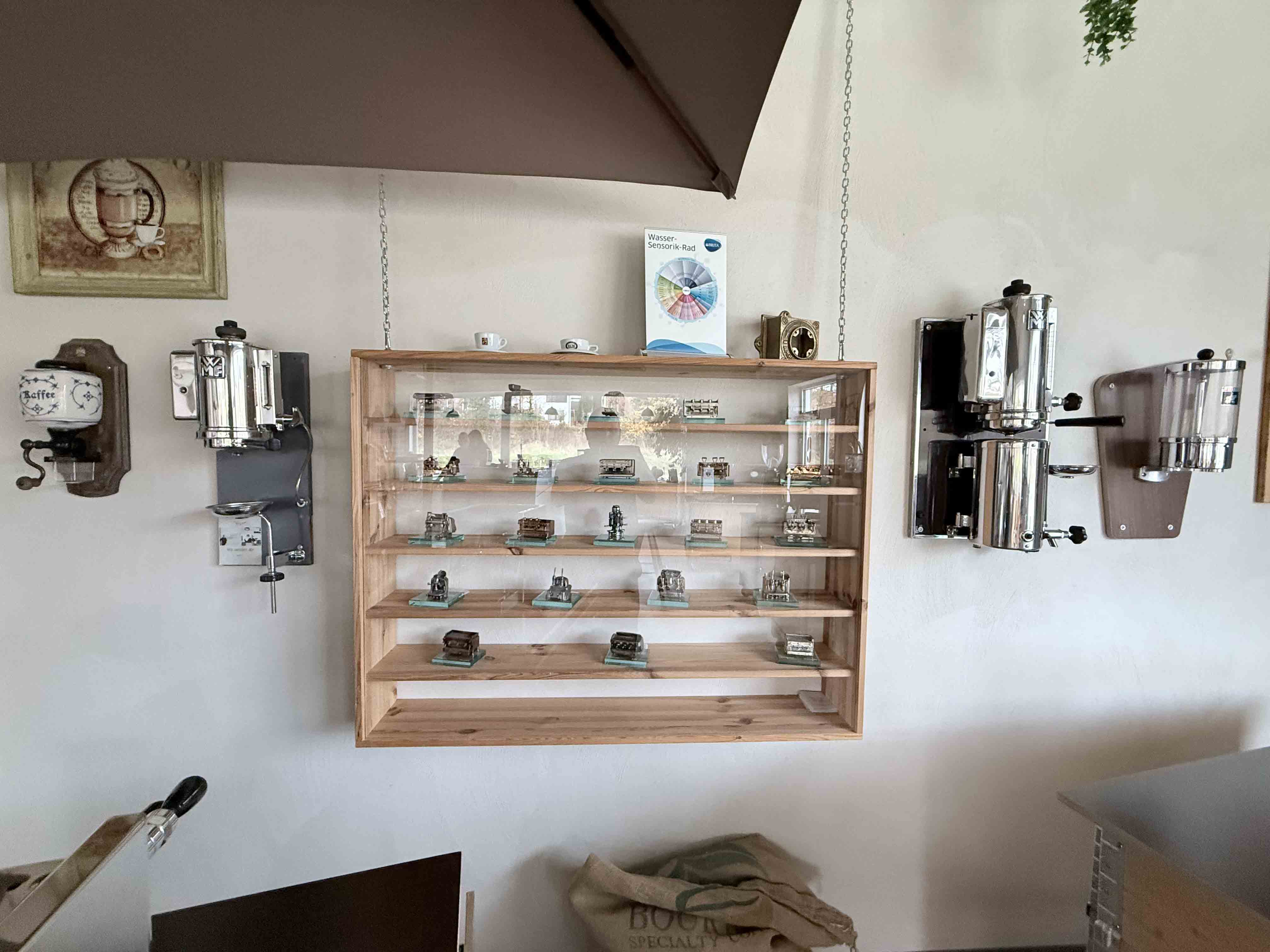 Wall display with vintage coffee machines and a glass cabinet containing small vintage machine models.