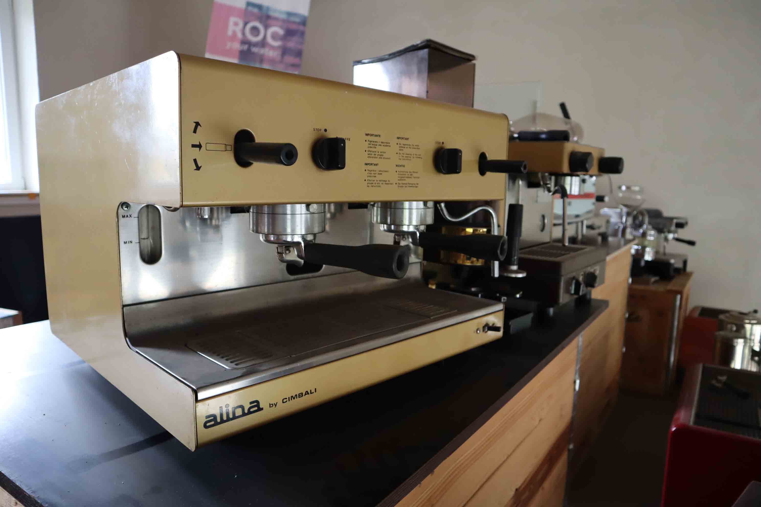 Vintage Alina by Cimbali espresso machine with dual portafilters on a wooden counter in a coffee setup.